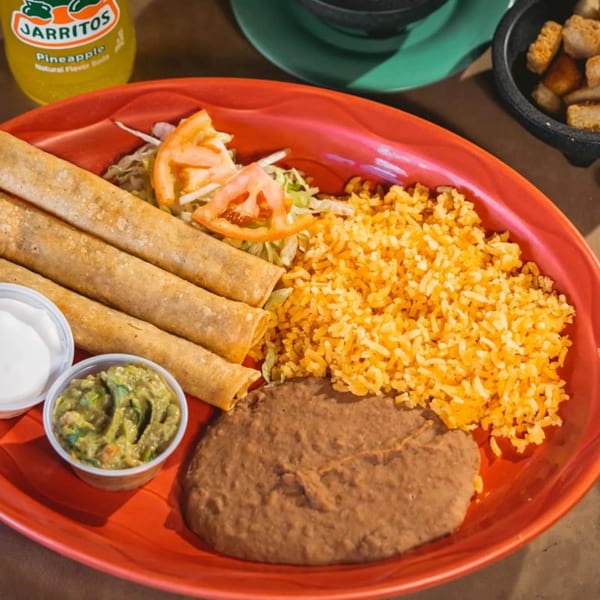 Mexican taquitos with rice, refried beans, guacamole, sour cream, and a Jarritos pineapple soda.