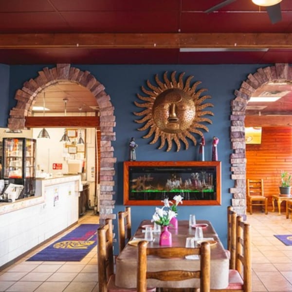 Interior of La Playita Mexican Restaurant with a golden sun decoration, fireplace, and dining tables.