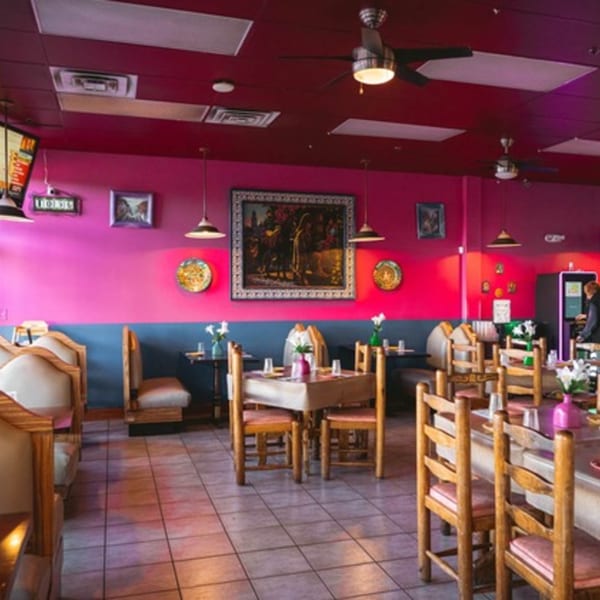 Colorful interior of La Playita Mexican Restaurant with pink and blue walls, wooden tables, and chairs.