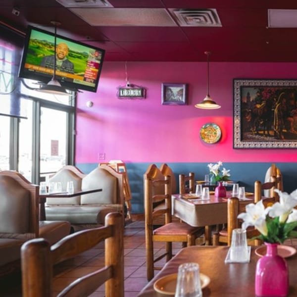 Vibrant La Playita Mexican Restaurant interior with pink and blue walls, wooden tables, and a TV.