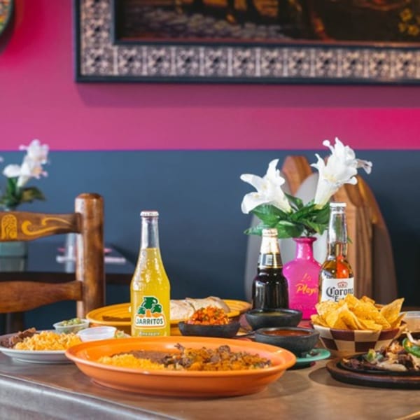A table at La Playita Mexican Restaurant with various dishes, Jarritos, and Corona beer.