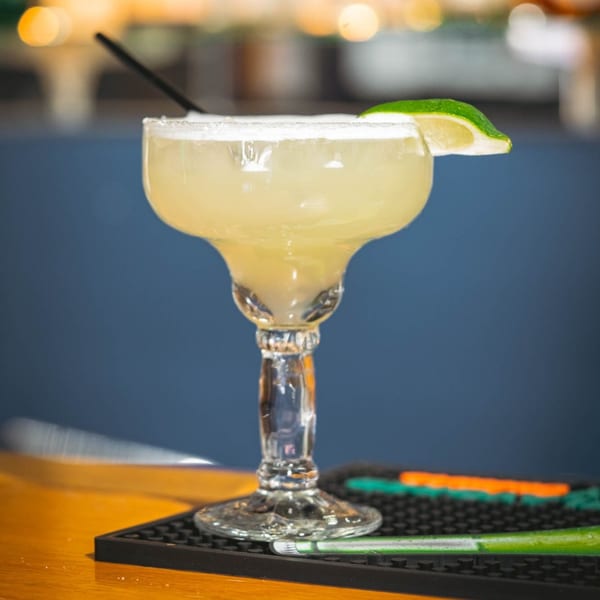 A La Playita Mexican Restaurant margarita with a salted rim and lime wedge on a bar.
